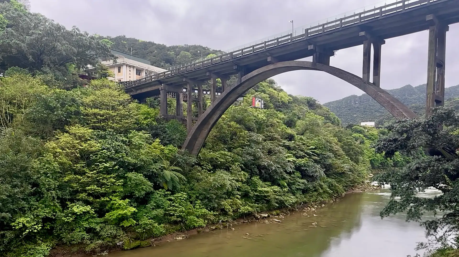 A tall concrete arch bridge extending across the river at Houtong Village, Taiwan.