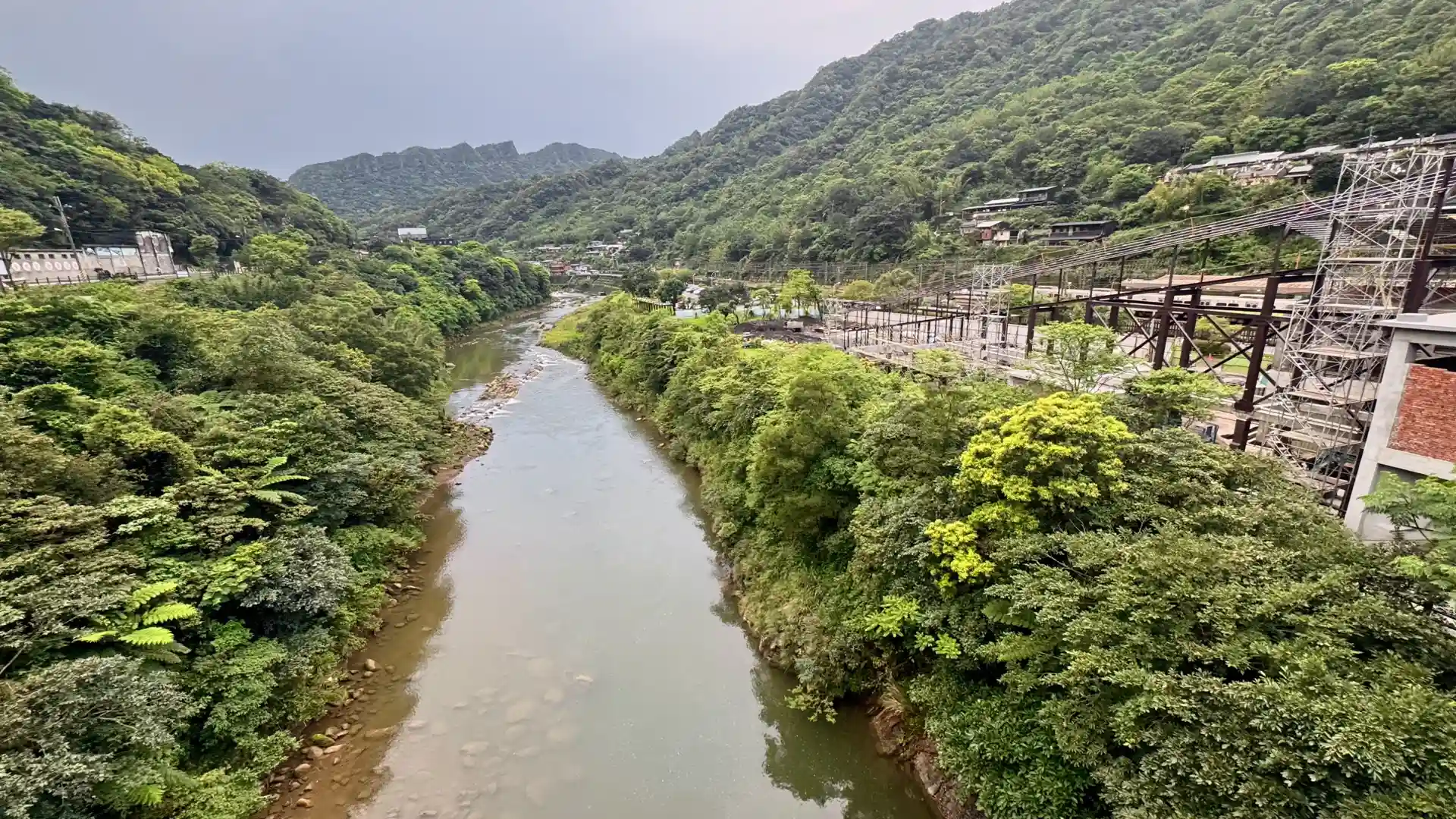 A calm dark green river next to Houtong Village.