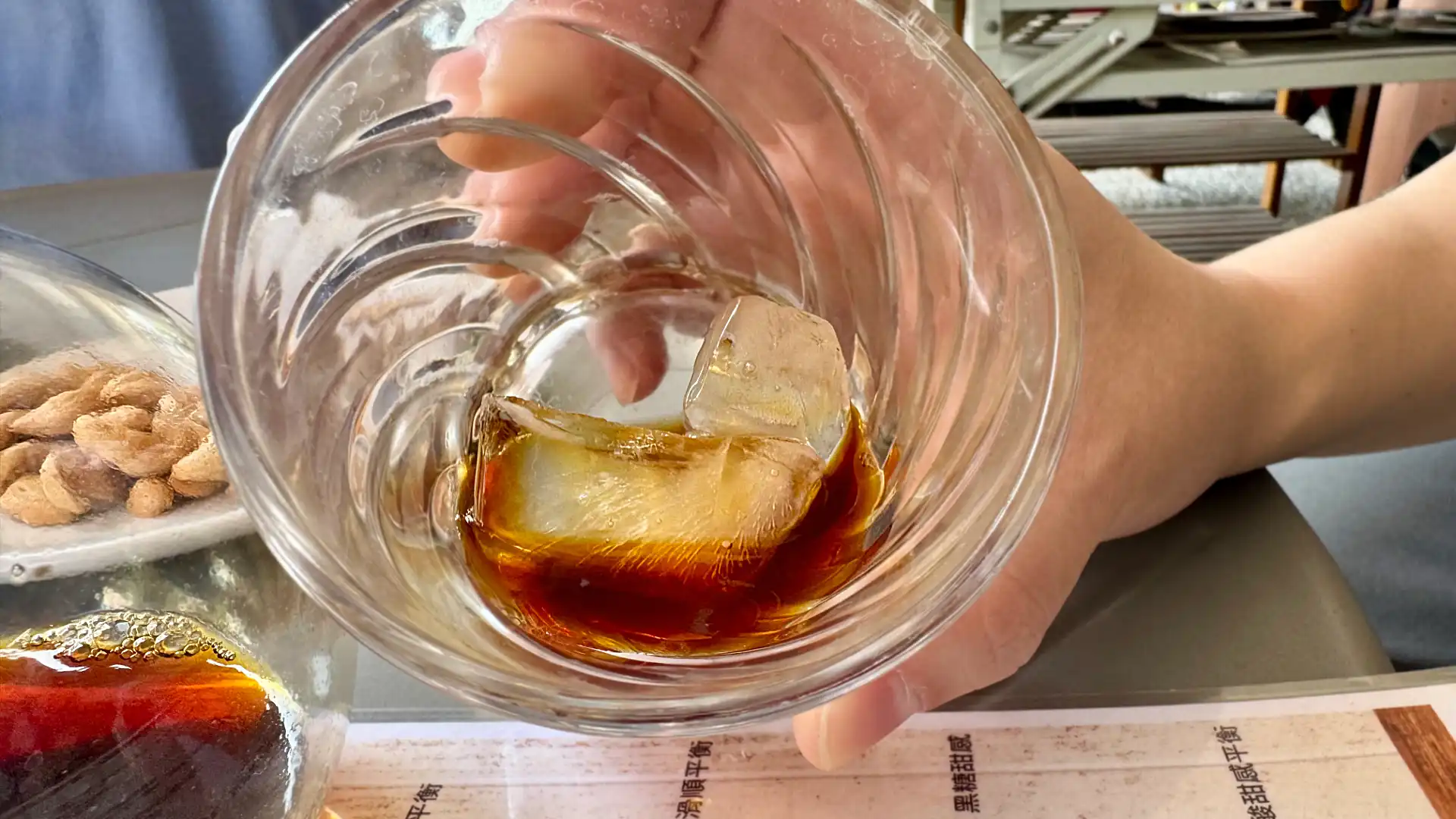 Close-up of rich reddish coffee with ice cubes in a glass.