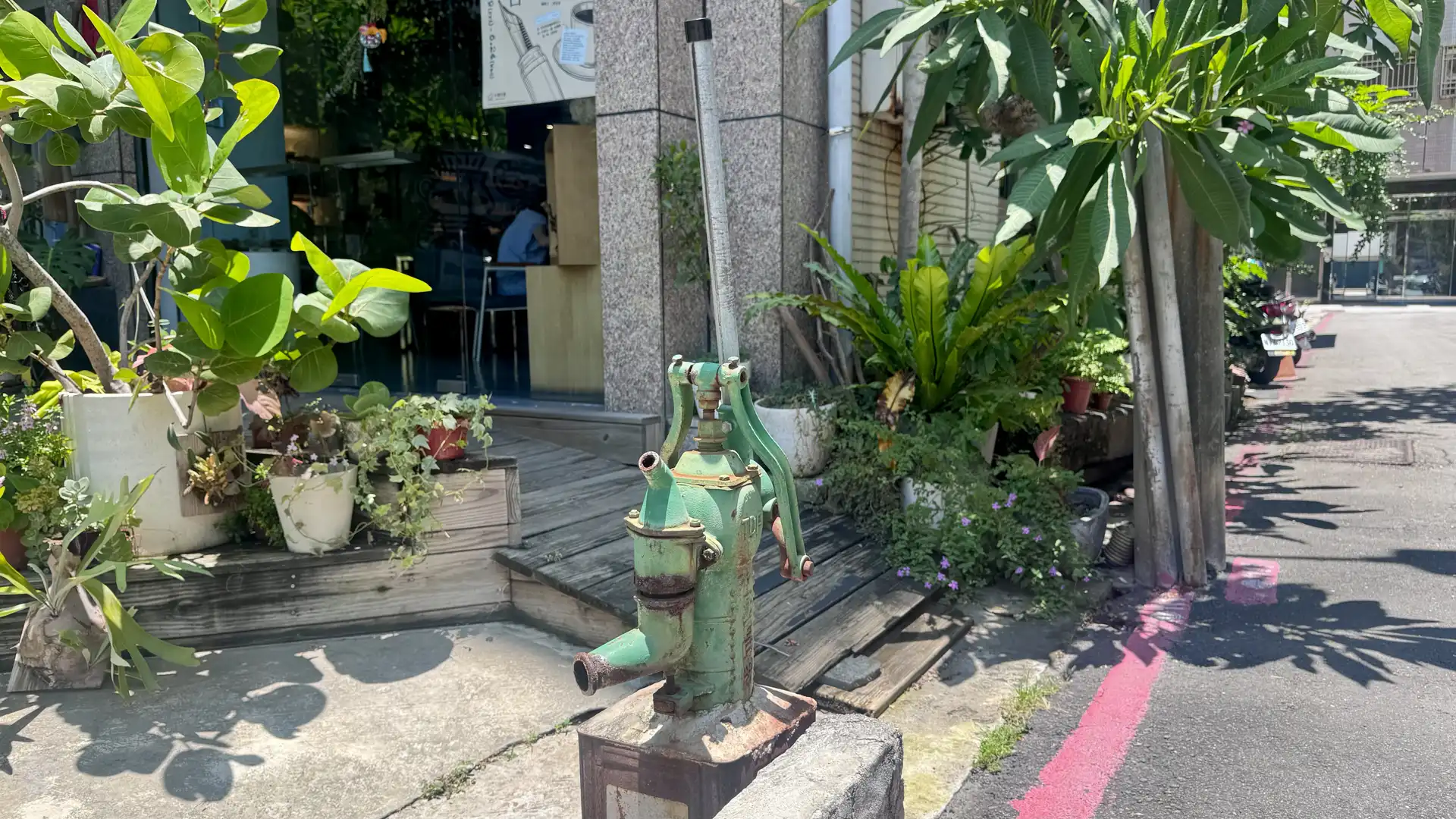 A cast-iron hand-operated water pump on a narrow urban street in Kaohsiung, Taiwan.