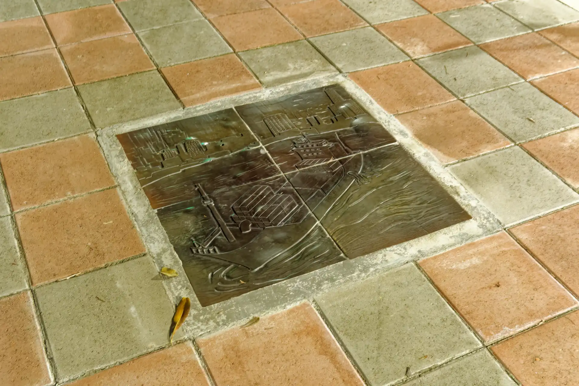 A bronze plaque embedded in a tiled sidewalk.