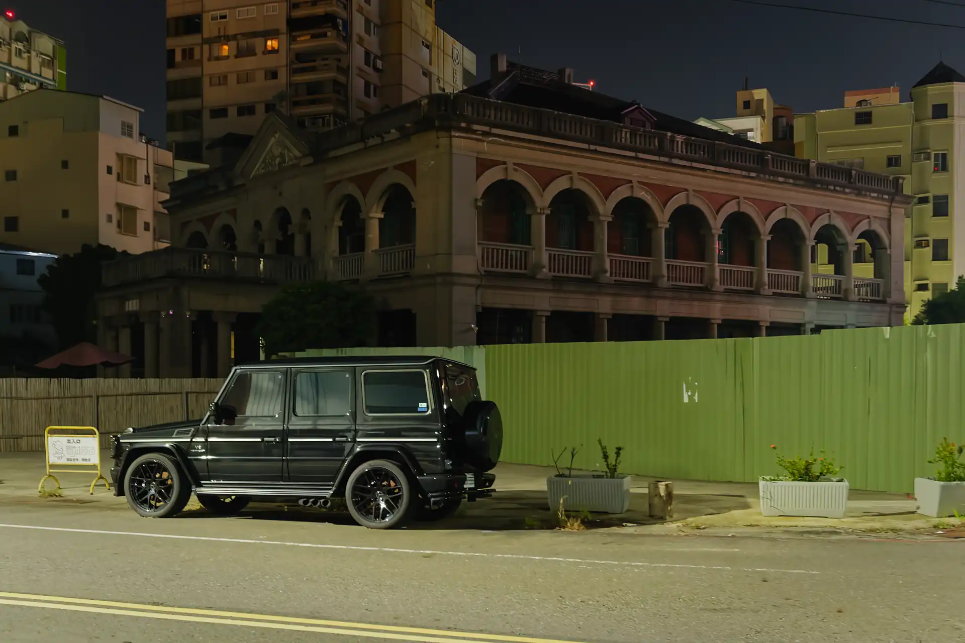 Chen Jhong-He Memorial Hall at night. The lower of two floors is obscured by a green steel fence around the property. The upper floor is surrounded by a wide arched verandah.