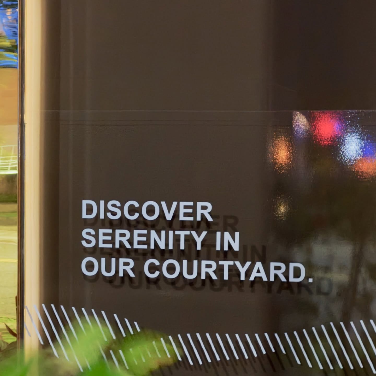 The words “DISCOVER SERENITY IN OUR COURTYARD” printed in upper-case on a real estate office window.