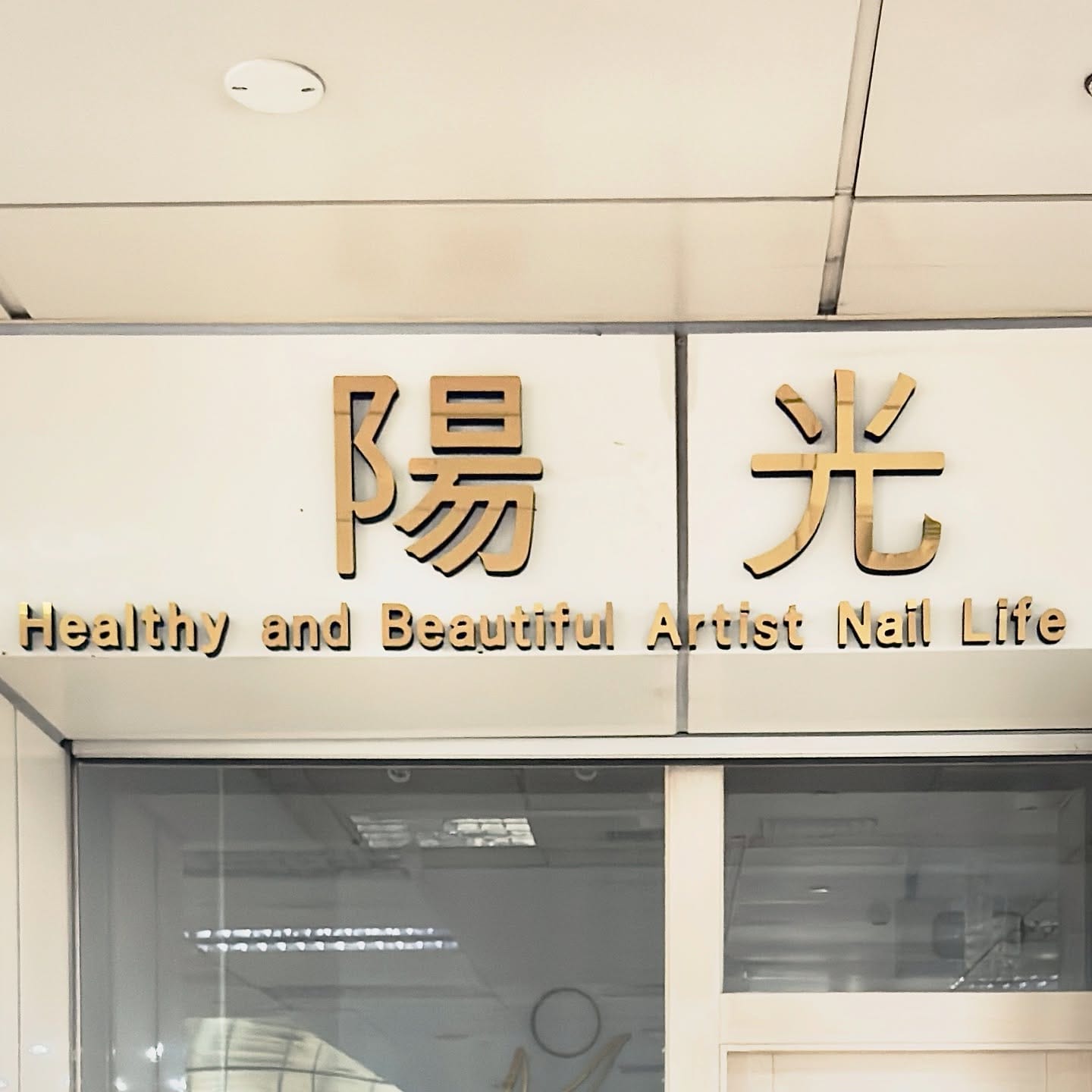 English sign above a building entrance that reads “Healthy and Beautiful Artist Nail Life”.