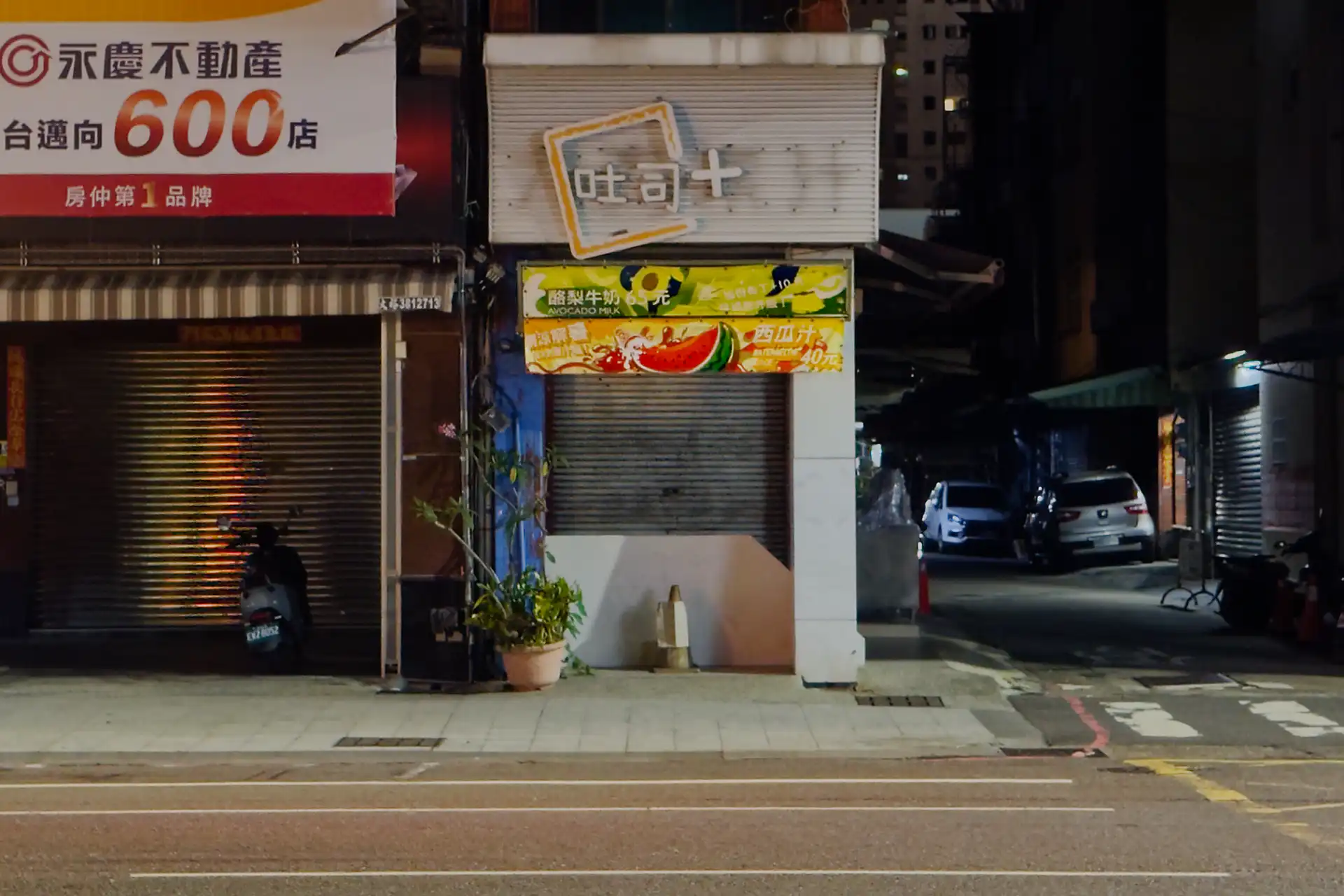 A narrow juice shop in Kaohsiung, Taiwan. The steel roller door covers the front at night, so it’s not obvious if it’s still actively trading or has permanently closed.