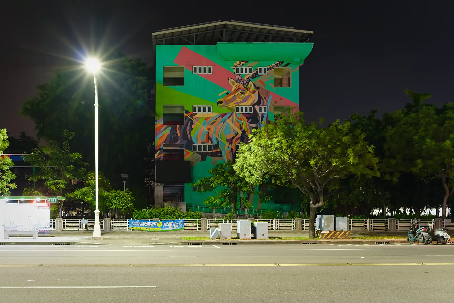 A four-story-tall mural on one end of a Taiwanese elementary school building. The mural shows a stylized multi-color deer looking into the distance.