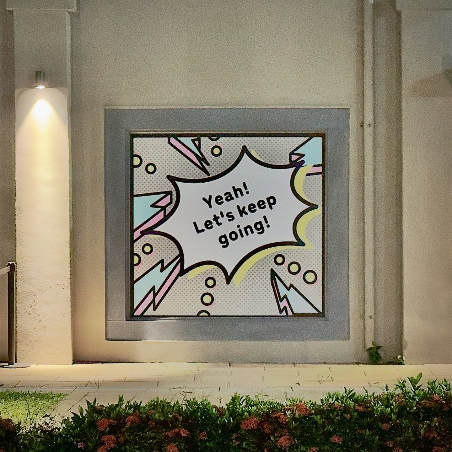 A comic book-style poster on a building which reads “Yeah! Let’s keep going!”