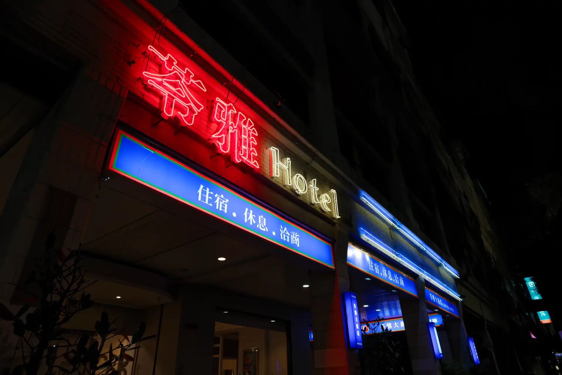 A neon red sign comprising Traditional Chinese characters, glowing on a hotel at night in Kaohsiung, Taiwan.
