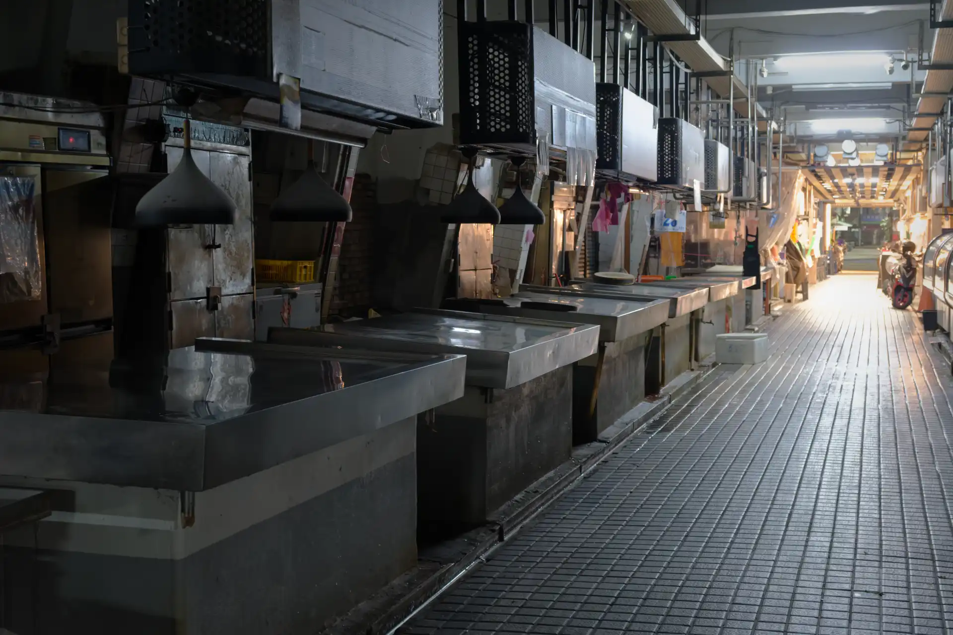 Empty stainless steel stalls at a deserted wet market at night.