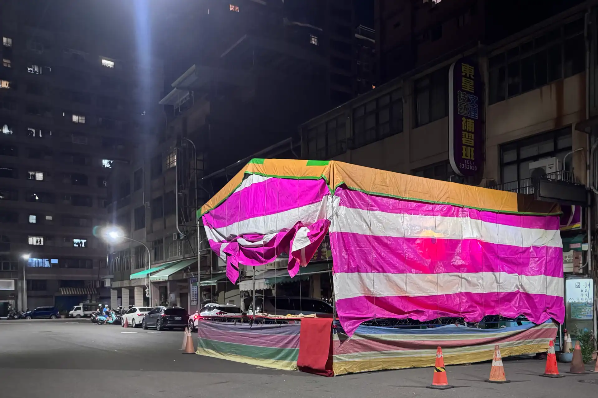A pink-and-white marquee set up on a side street in Kaohsiung, Taiwan. It blocks one lane of the two-lane street.