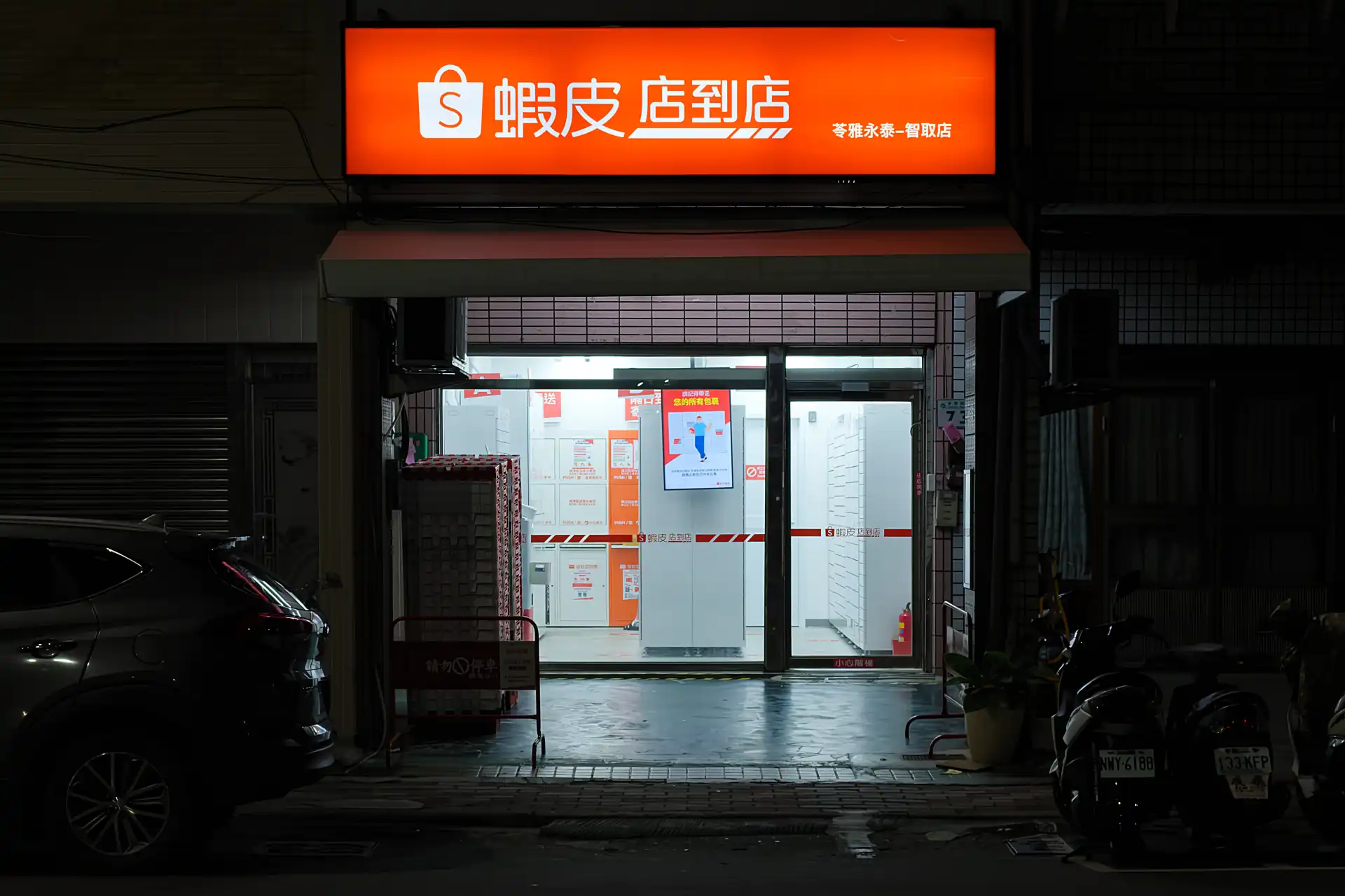 An unmanned Shopee collection point at night. It is brightly lit and contains rows of locked lockers.