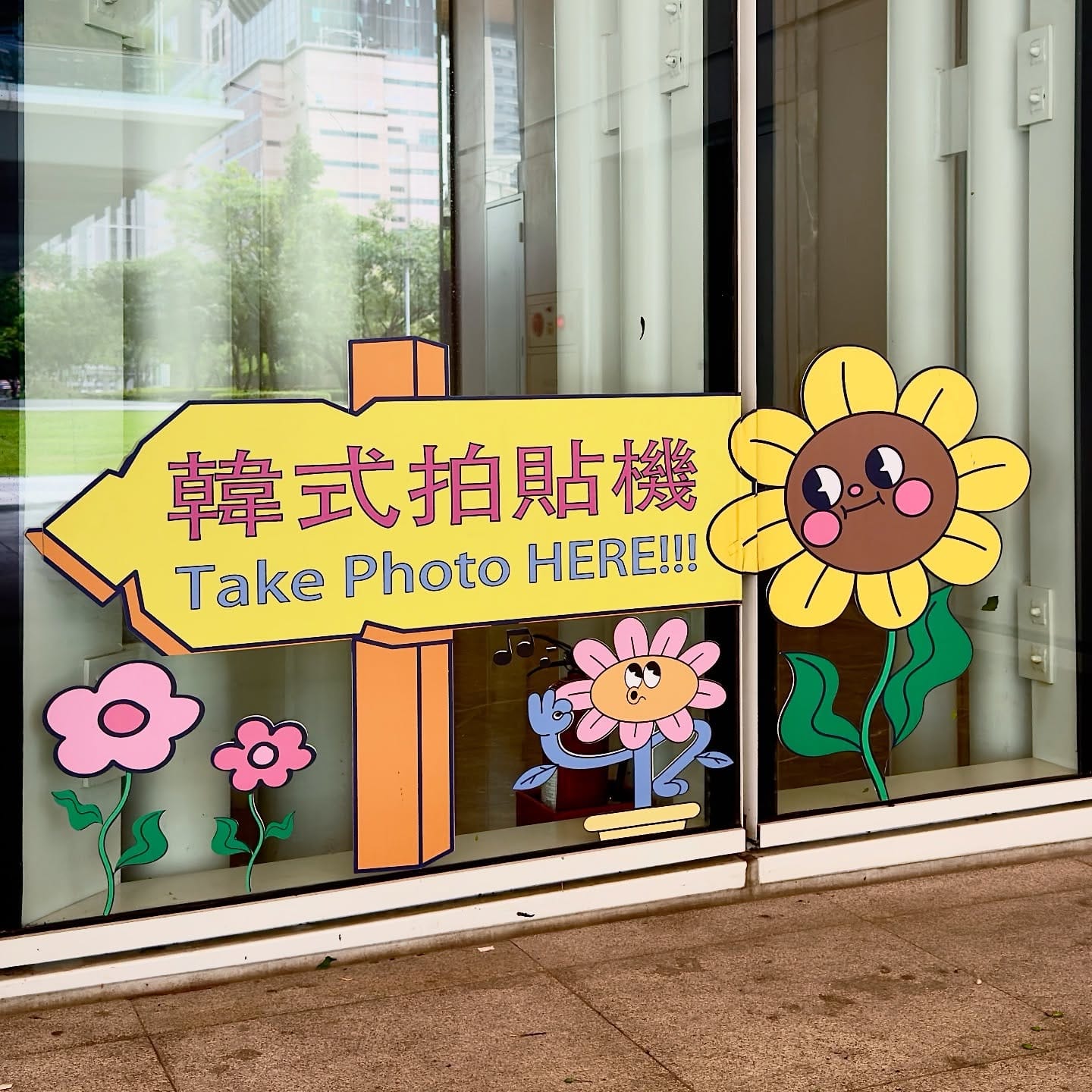 A cartoon signpost on an exterior window, which reads “Take Photo HERE!!!” (with three exclamation points after “HERE”).