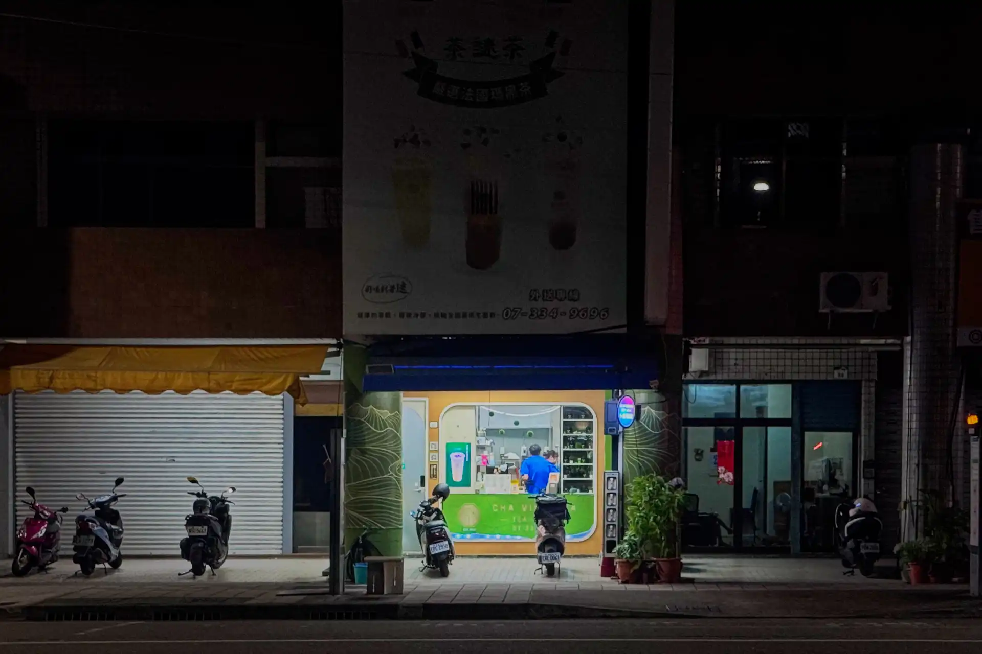 Two employees working at a take-out tea shop in Kaohsiung, Taiwan, at night.