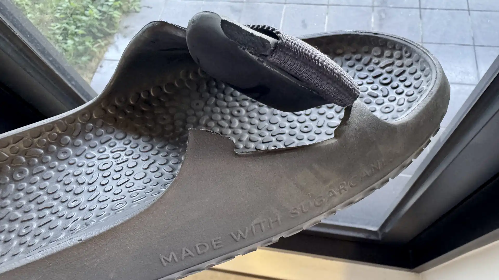 Close-up of a broken upper strap on an Allbirds Sugar Slider, with “Made with Sugarcane” imprinted on the sole.