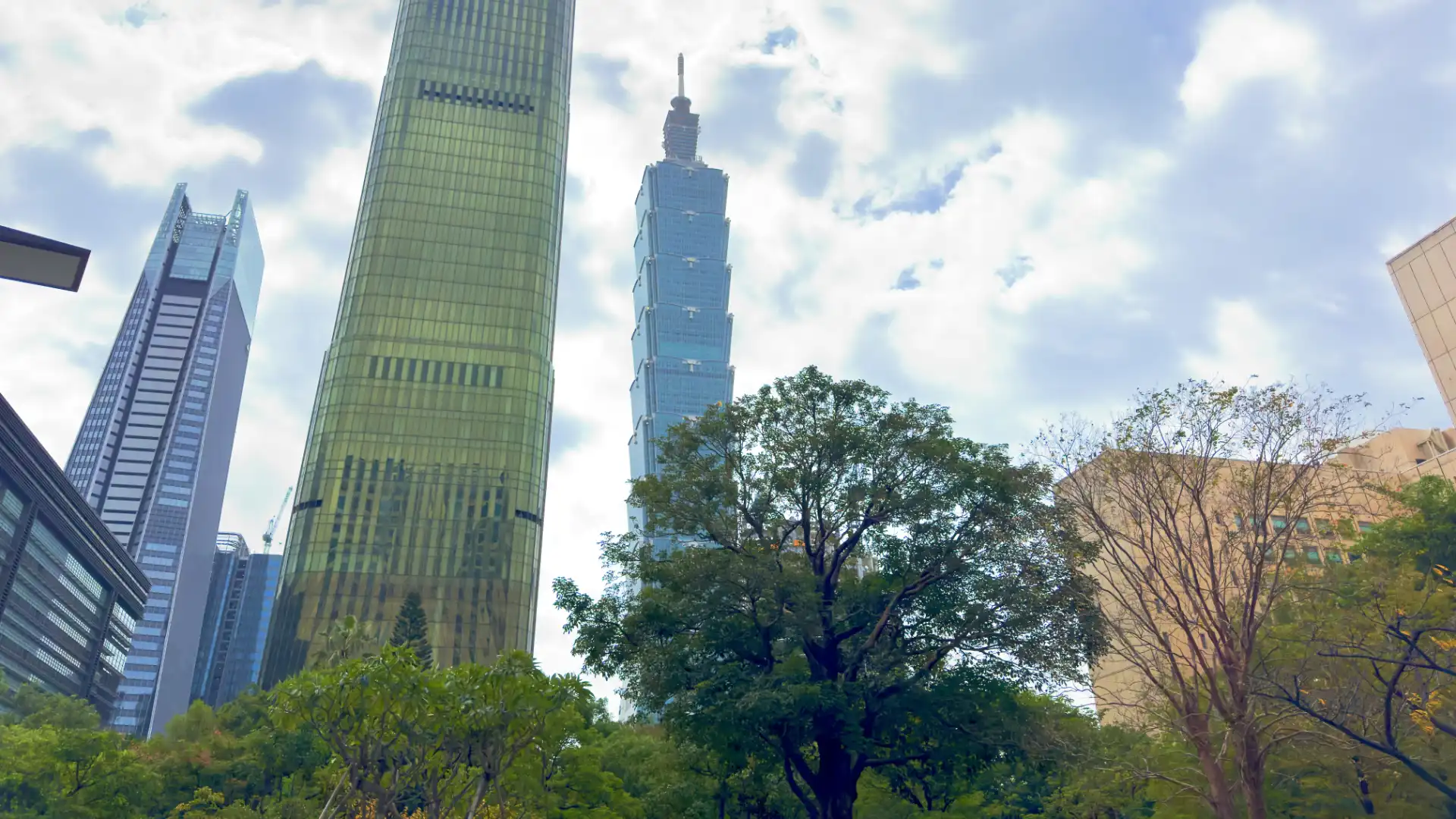 Taipei 101 and other sky scrapers visible above green trees in the foreground.