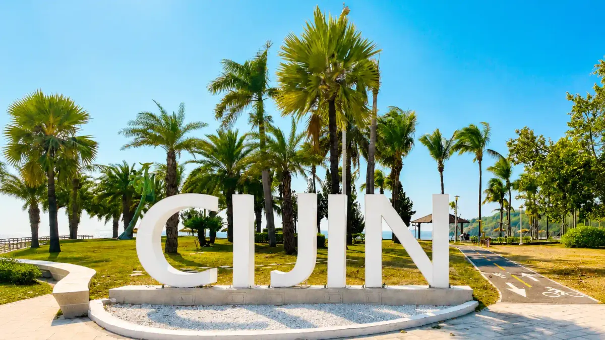 Large white “CIJIN” landmark sign in a palm-lined waterfront park on Cijin Island, Kaohsiung, Taiwan.