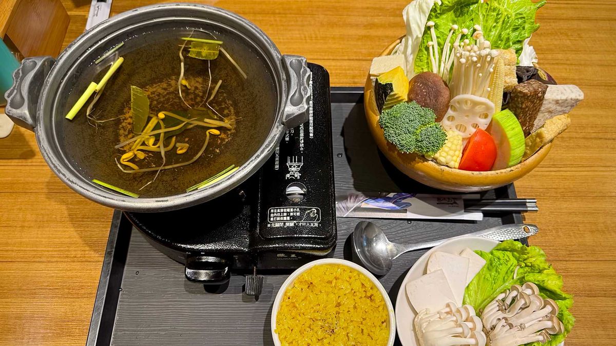 A tray of vegan hotpot ingredients and a bowl of lemongrass broth on a portable gas stove, at a Taiwan restaurant.