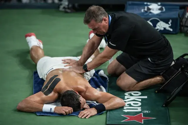Injured tennis player assisted by the physio.