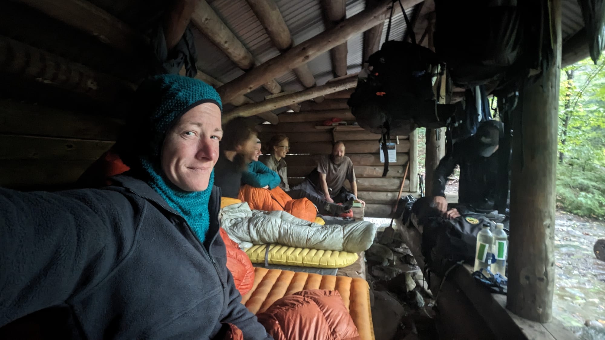 Thru-hiker resting inside an Appalachian Trail shelter during wet weather in Maine.
