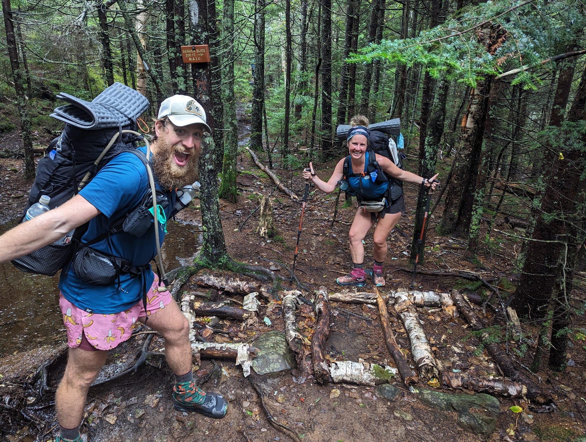 Backpacker hiking over exposed roots and rocks on the Appalachian Trail in Maine.