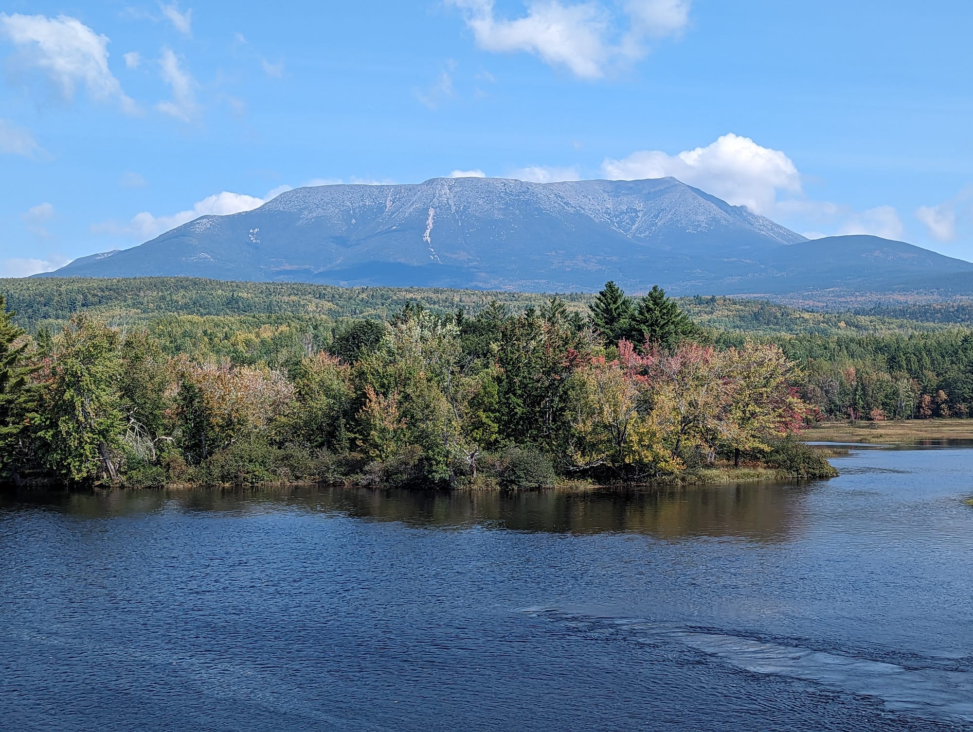 Mount Katahdin rising above early autumn forest and a blue Maine lake from the Appalachian Trail.