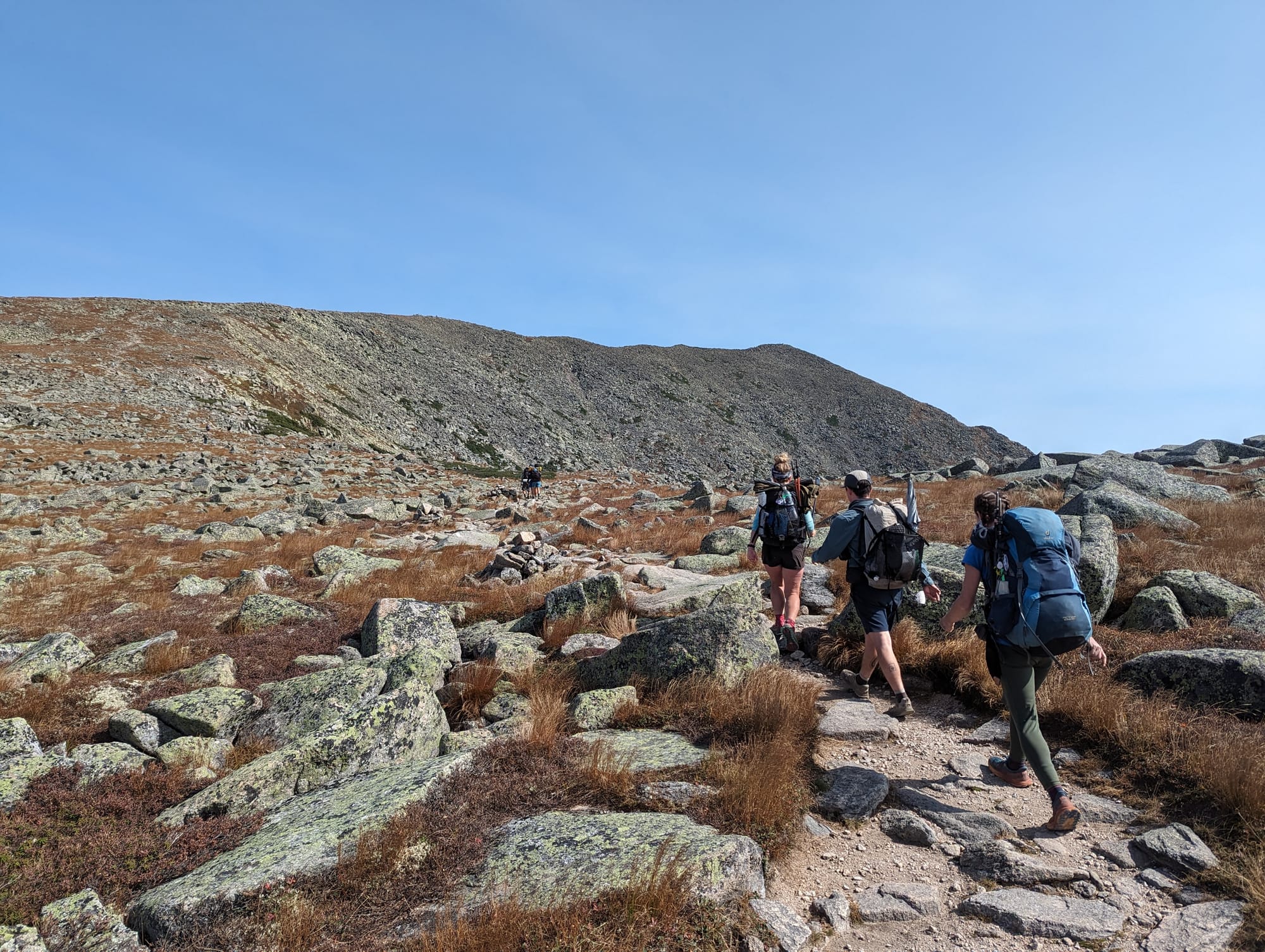 Backpackers hiking across the rocky Tableland near the summit of Mount Katahdin.