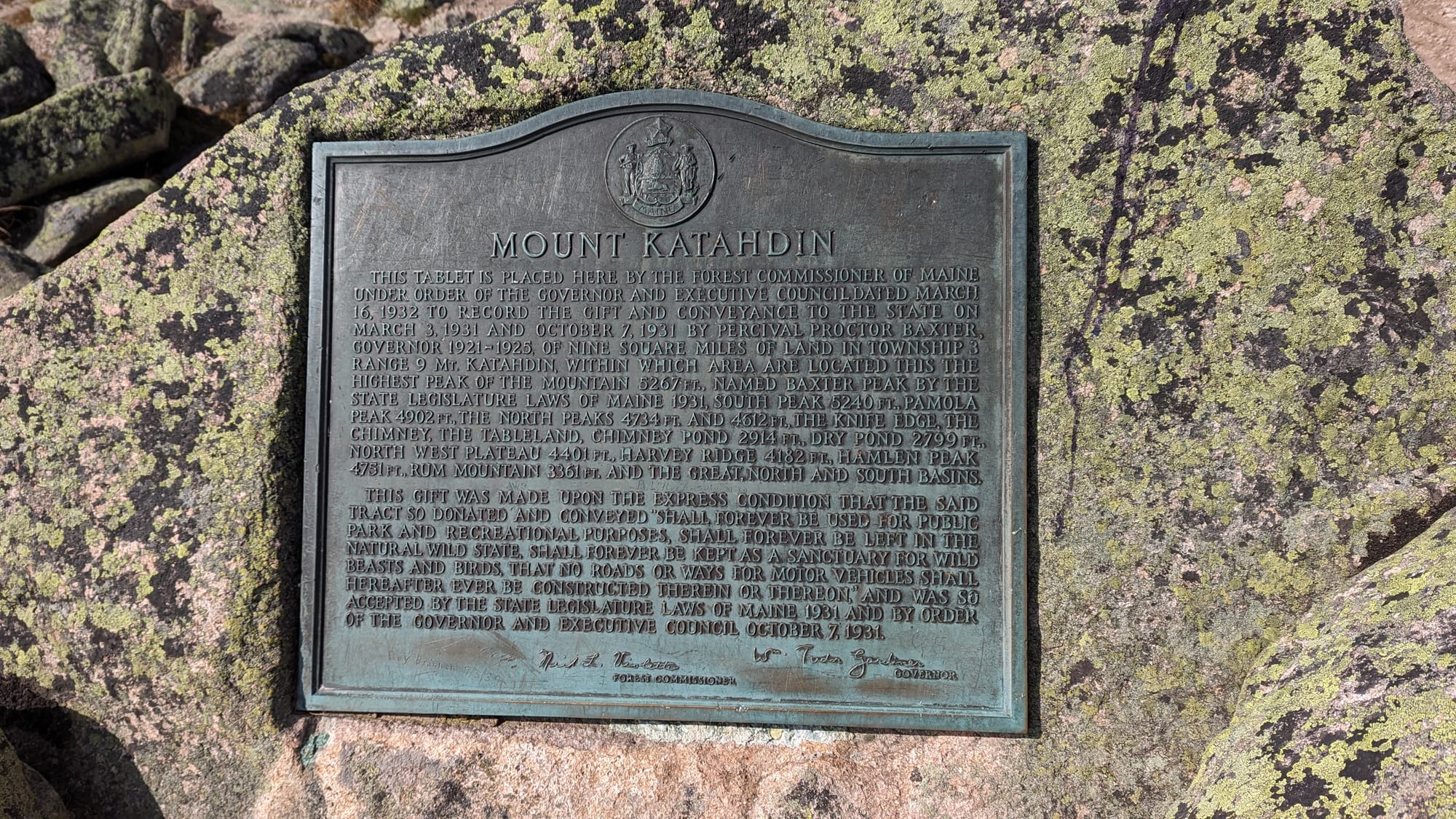 Bronze Mount Katahdin marker set into lichen-covered granite in Baxter State Park.