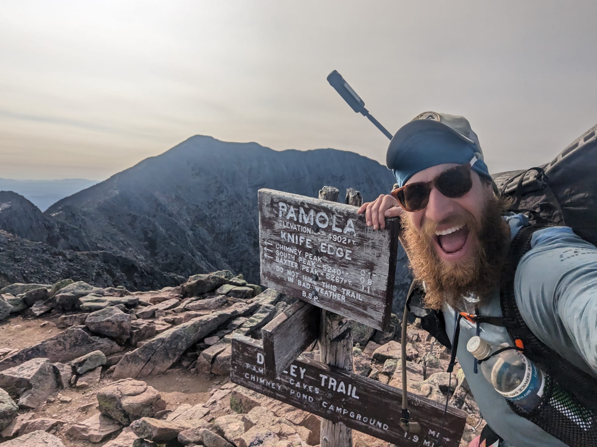 Brandon beside the Pamola Peak and Knife Edge trail signs on Mount Katahdin.