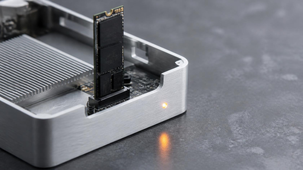 Matte black M.2 SSD seating into brushed aluminum enclosure with amber LED, no people. Hire Founding Engineer