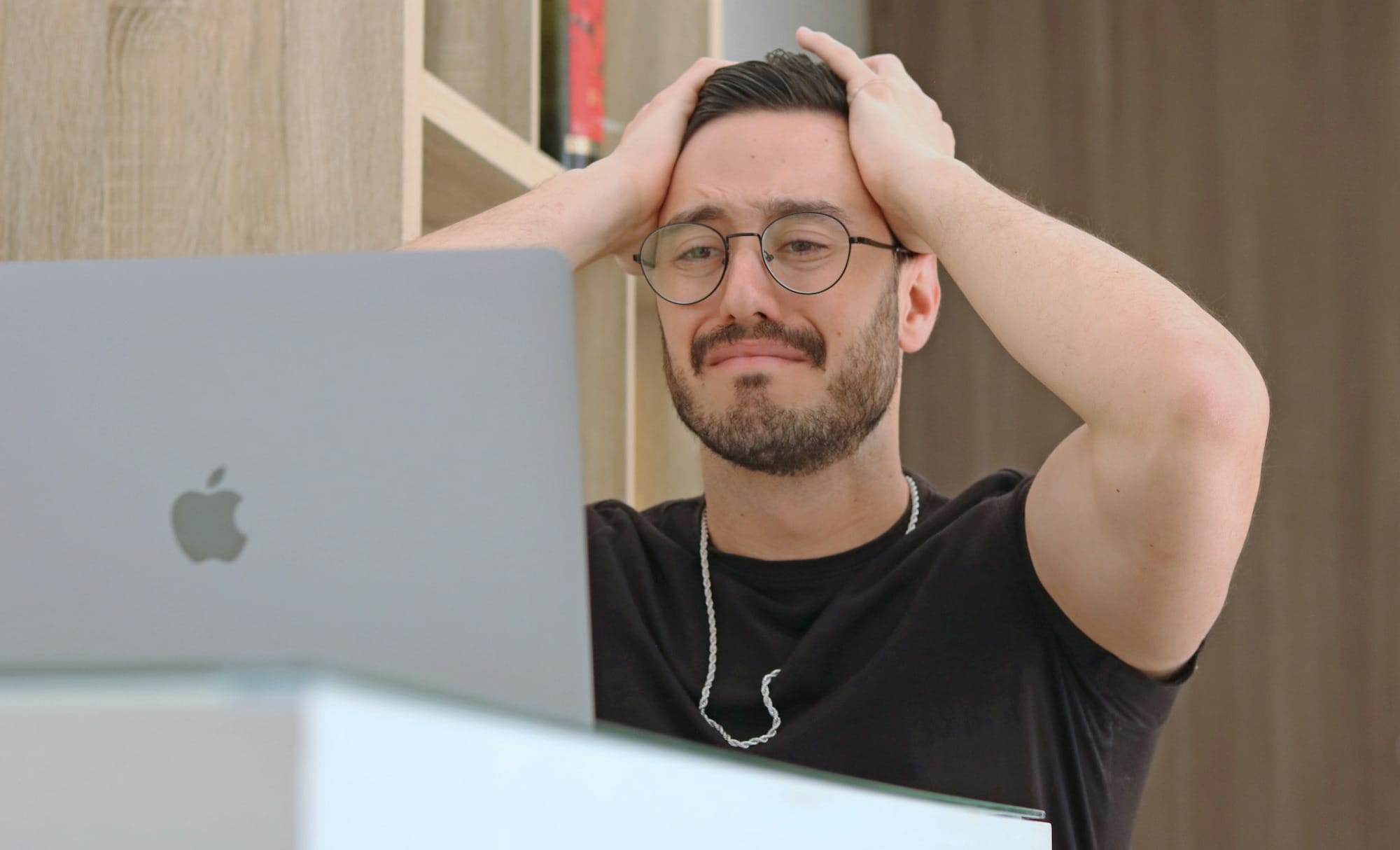 a man with glasses is looking at a laptop
