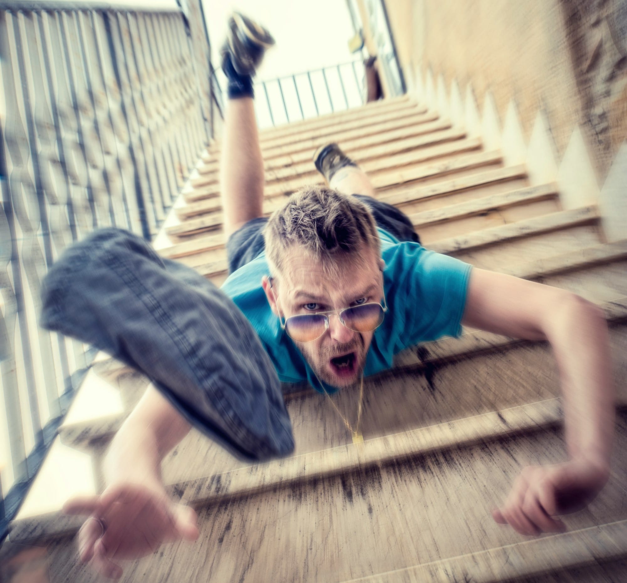 man in blue t-shirt and blue denim shorts sitting on concrete stairs during daytime