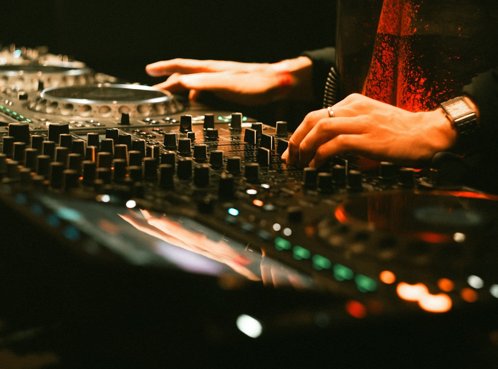 Dj mixing music on a soundboard with hands.
