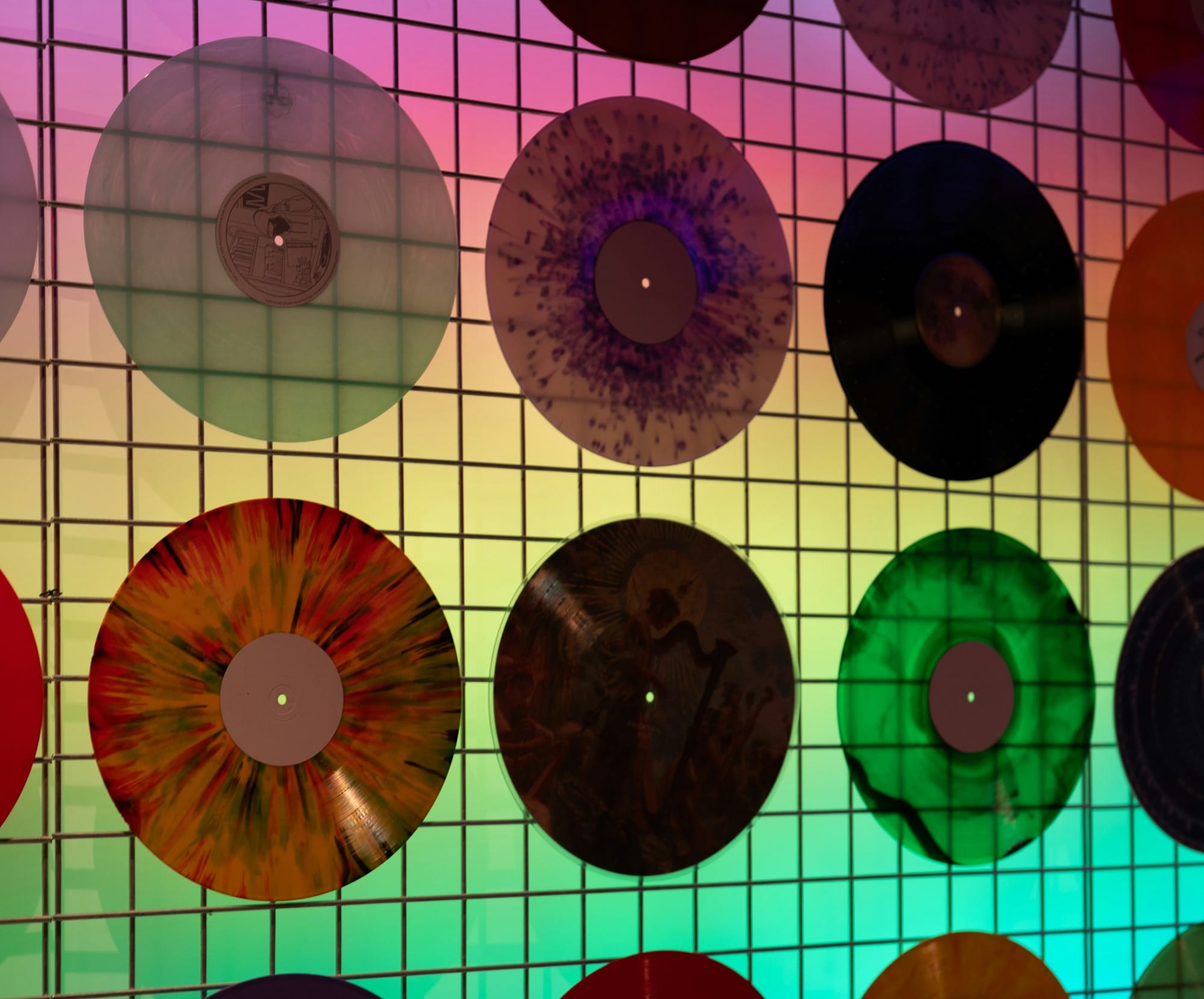 Colorful vinyl records displayed on a grid wall.