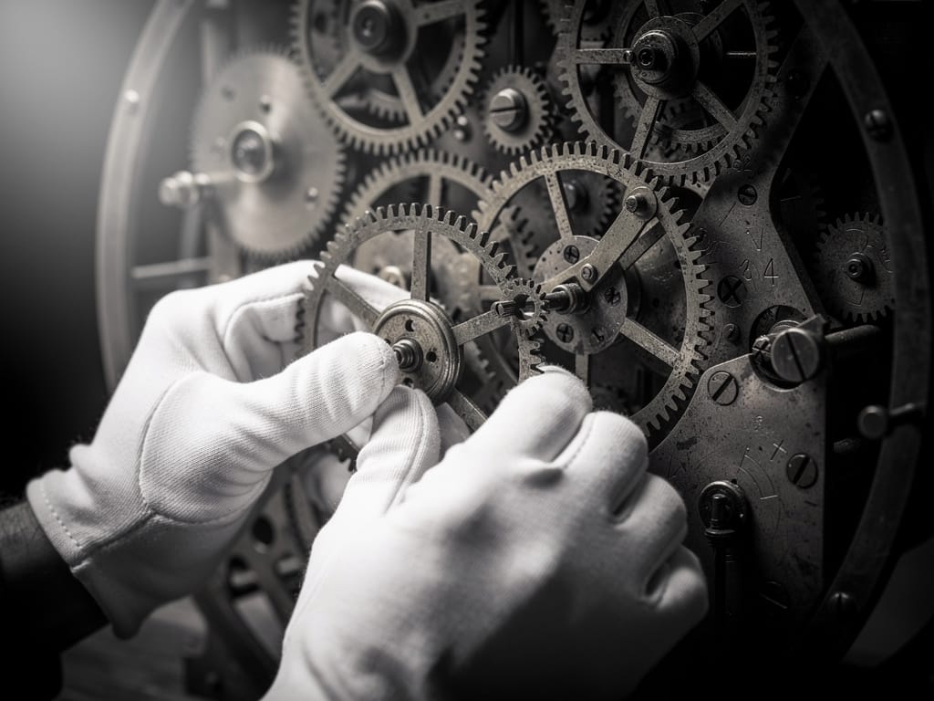 Hands carefully placing a new gear into a complex clockwork machine