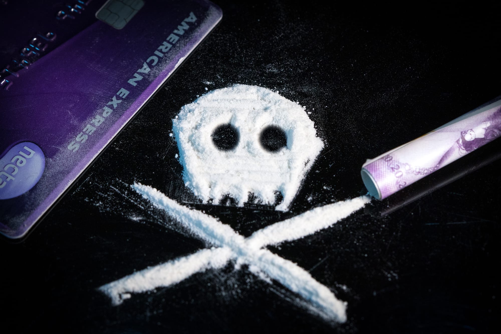 Skull and crossbones made of white powder drugs.