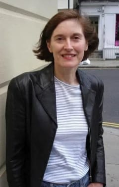 Author Nicole Swengley smiling and looking at the camera wearing a blazer and striped shirt.