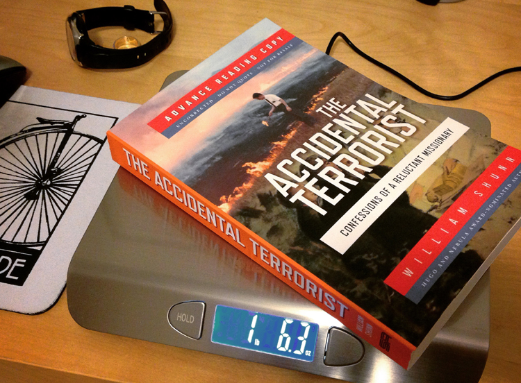A trade paperback copy of The Accidental Terrorist, labeled "Advance Reading Copy," rests atop a digital scale which reads 1 pound 6.3 ounces.