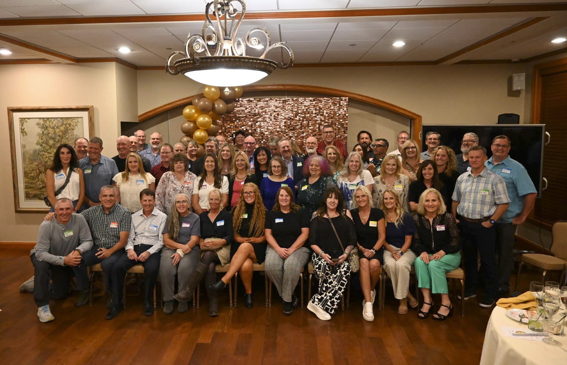 A whole lot of old people gather in a banquet room for a group photo.