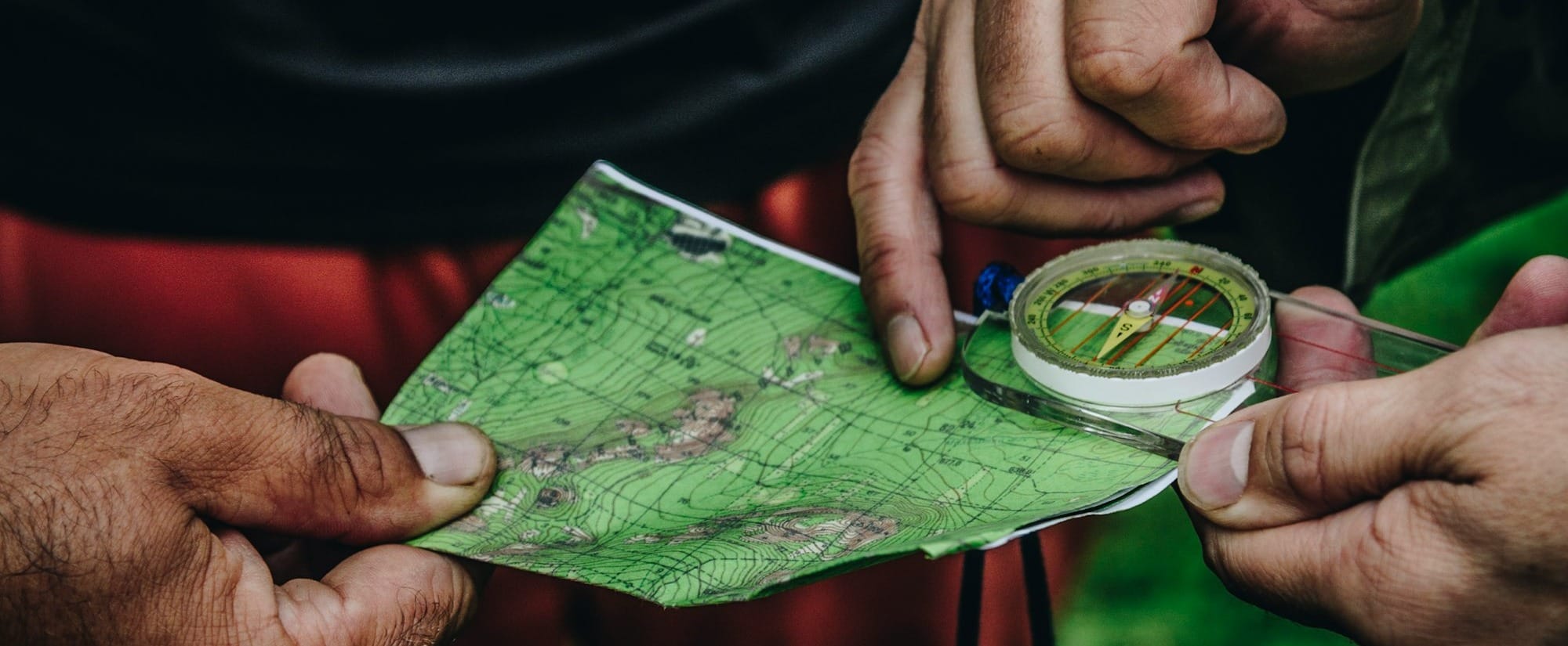 two person holding map and clear compass
