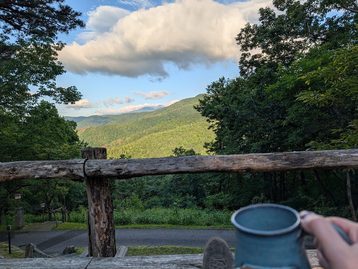 Me drinking coffee while looking out over a gloriously green mountain topped with fluffy cliche clouds.