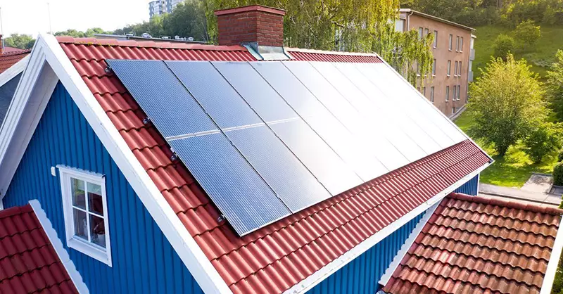 Solpaneler installerade på ett blått hus med rött tak