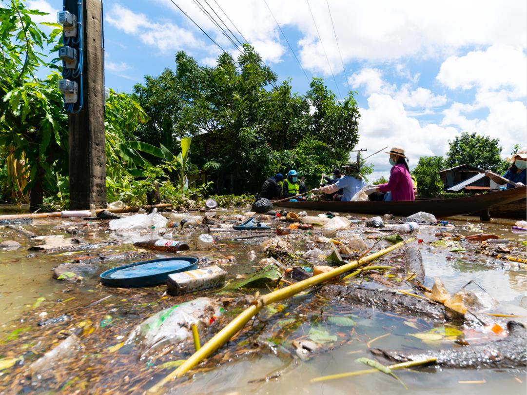People in a canoe on floodwater, the floodwater is brown and filled with different kinds of pollution