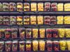 Four supermarket shelves are lined with plastic tubs full of chopped fruits. From left to right, each shelf displays the…