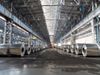 An interior shot of the production shop at an aluminium plant. Rolls of aluminium are placed in rows extending away from…