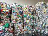 Four large bales of recycled plastic packaging. Various bags, bottles, and tubs have been crushed and tied together at a…