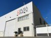 An exterior shot of Pusa Pack's liner bag plant. It is a white building with grates on the windows and the Pusa Pack logo…