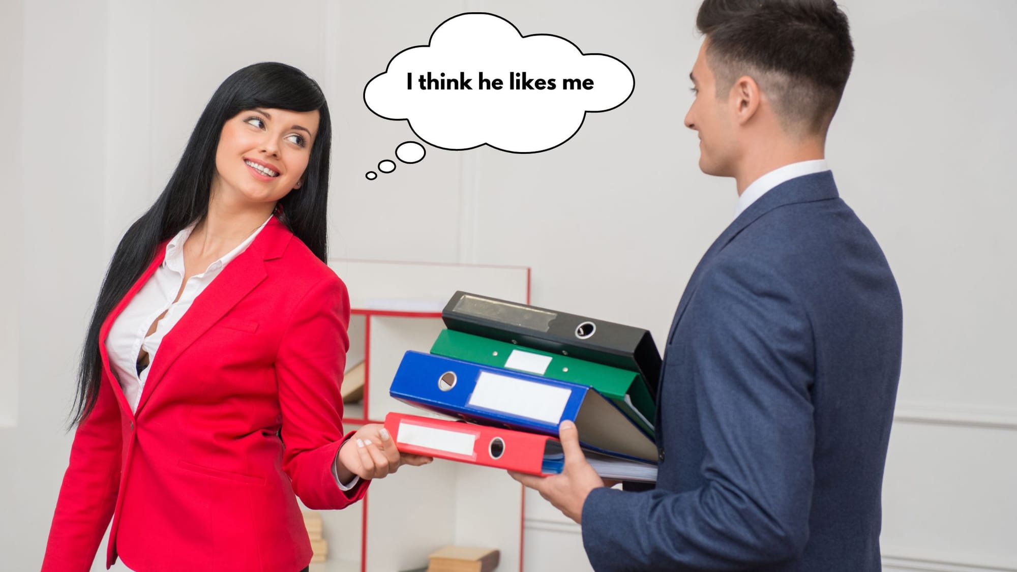 A woman in a red blazer smiles at a male coworker holding folders, with a thought bubble saying “I think he likes me.”