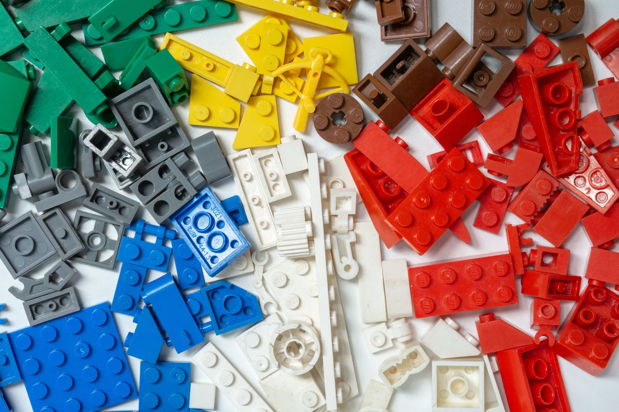 Bunte Lego Steine liegen verstreut auf einem weißen Tisch
