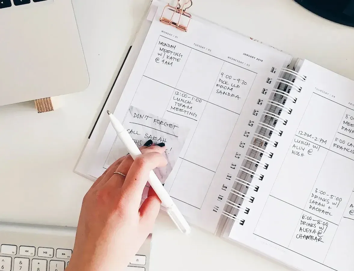 Frau hält Stift in der Hand und blättert in ihrem Kalender