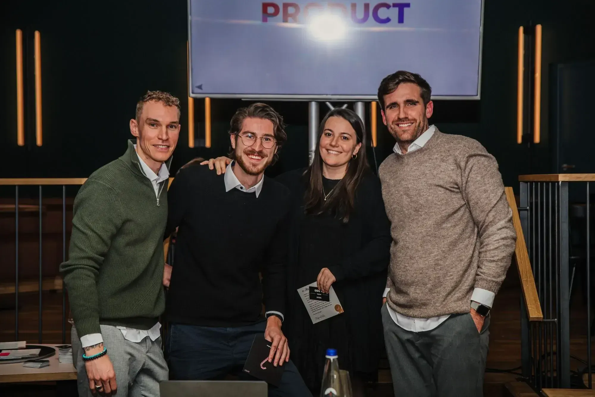 3 Männer und 1 Frau in formeller Kleidung stehen beisammen Arm in Arm und lassen sich fotografieren